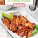 Air fryer sweet and spicy chicken wings and lemon wedges in a serving dish.
