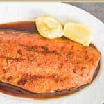 Baked salmon and two lemon wedges on a platter.