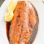 Homemade baked salmon and lemon wedges on an oval platter.