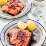 Copycat Cheddar's bourbon glazed salmon and lemon wedges on two plates.