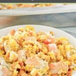 Homemade chicken and dressing casserole serving in a bowl next to the casserole.