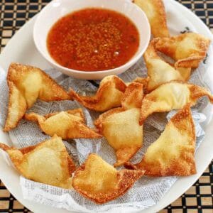 Cream cheese wontons and a small bowl of dipping sauce.
