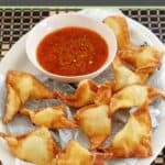Homemade cream cheese wontons with dipping sauce on a platter.