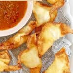 Homemade cream cheese wontons on parchment paper.