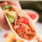 Hand holding a taco made with crockpot chicken taco filling.