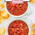 Crockpot chili in two bowls and Frito corn chips scattered around them.