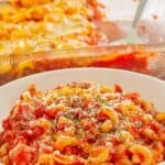 A serving of cheesy ground beef casserole in a bowl in front of the dish.
