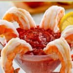 Homemade cocktail sauce and peeled shrimp in a martini glass.