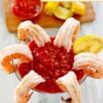 Homemade cocktail sauce, shrimp, and a lemon wheel in a martini glass.