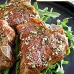 Lamb chops over arugula on a platter.