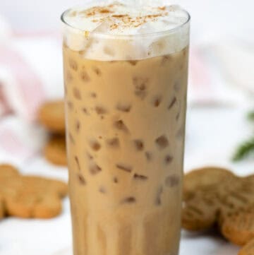 Copycat Starbucks gingerbread oat milk chai latte in a tall glass and cookies behind it.