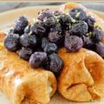 Homemade cheese blintzes topped with blueberries and lemon zest.