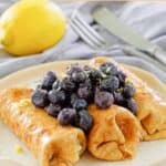 Three cheese blintzes topped with blueberries.