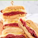 Two homemade corned beef breakfast sandwiches cut in half and on a wood board.