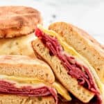 Corned beef breakfast sandwich cut in half on a wood board.
