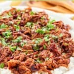 Instant pot pulled pork on a platter garnished with parsley.