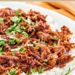 Instant pot pulled pork over rice on a plate.