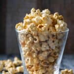 Homemade karo syrup caramel popcorn in a glass and scattered around it.