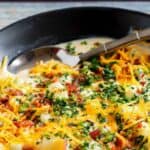 A bowl of copycat O'Charley's loaded potato soup with a spoon in it.