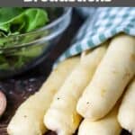 Homemade Olive Garden breadsticks and a salad next to them.