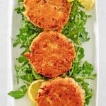 Old fashioned salmon patties and arugula on a platter.