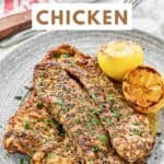 Homemade Texas Roadhouse herb crusted chicken breasts and grilled lemon halves on a plate.