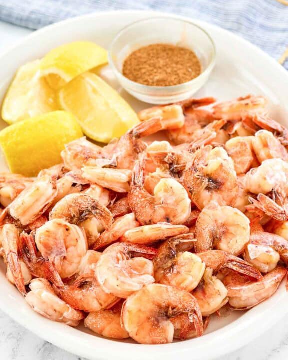 Boiled shrimp served with lemon wedges on a platter.