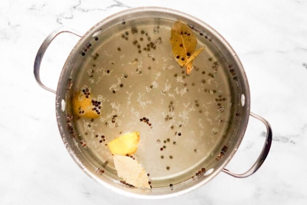 Garlic, kosher salt, black peppercorns, bay leaves, and lemon wedges in a large pot of water.
