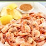 Boiled shrimp, lemon wedges, and a small cup of seafood seasoning.