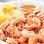 Boiled shrimp, lemon wedges, and a small bowl of seasoning.