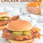 Homemade Chick Fil A spicy chicken sandwich and a basket of waffle fries behind it.