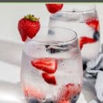 A glass of berry infused water, blueberries, and strawberries.