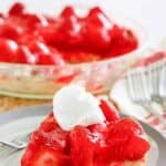 Homemade big boy strawberry pie and a slice on a plate in front of it.
