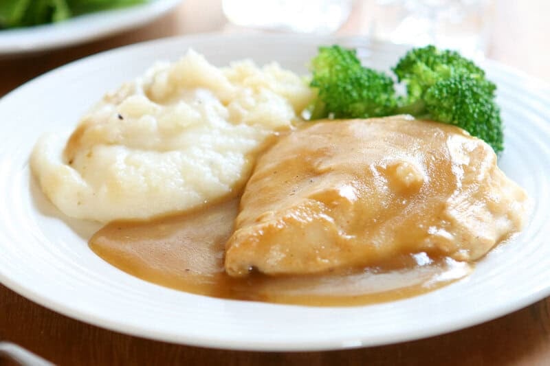 Homemade chicken gravy on top of a roasted chicken breast.