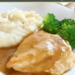 Chicken covered in homemade chicken gravy on a plate with potatoes and broccoli.