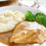 Homemade chicken gravy on a plate with chicken, mashed potatoes, and broccoli.