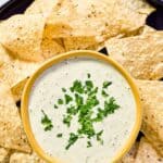 Homemade Chuy's creamy jalapeno dip with tortilla chips on a round platter.