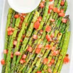 Copycat olive garden parmesan roasted asparagus with dipping sauce on a platter.