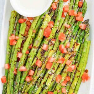 Copycat olive garden parmesan roasted asparagus with dipping sauce on a platter.