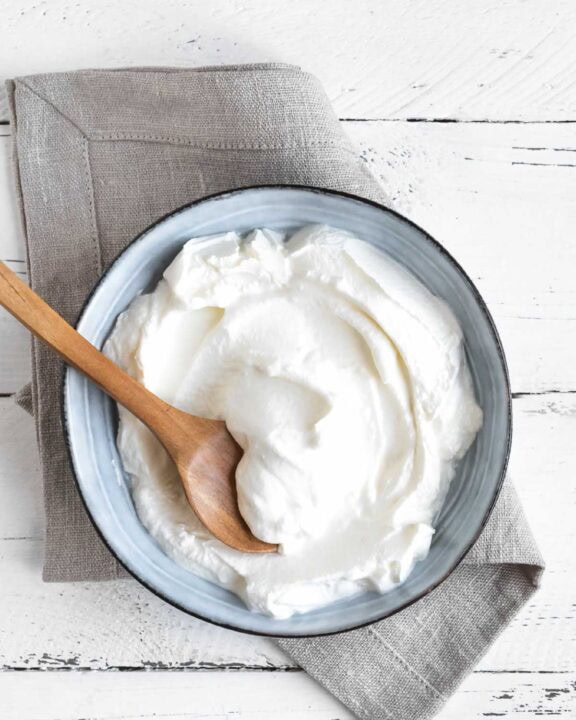 Sweetened vanilla yogurt in a bowl on a wood surface.