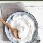 A bowl of sweetened yogurt on a wood surface.