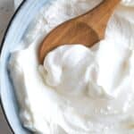 A wooden spoon in a bowl of sweetened yogurt.