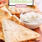 Homemade Taco Bell steak quesadilla and a small cup of sour cream.