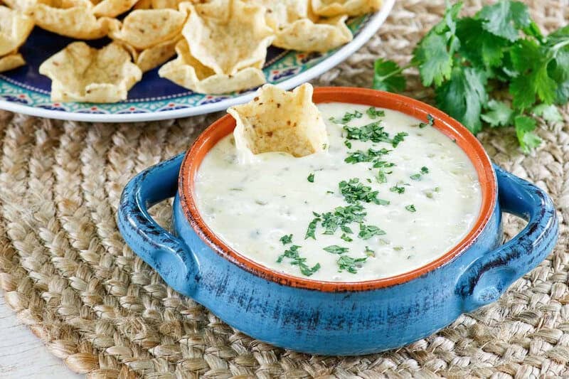 Homemade white queso dip, tortilla chips, and fresh cilantro.