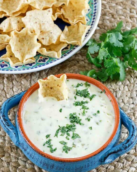 Homemade white queso dip and a plate of tortilla chips.
