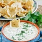 A bowl of homemade white queso dip and a plate of tortilla chips.
