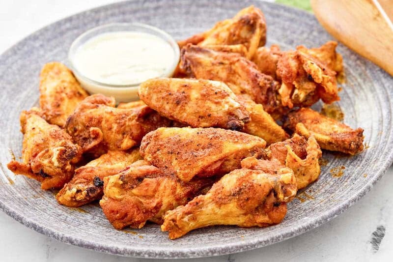 A plate of copycat Wingstop Louisiana rub wings with dipping sauce.