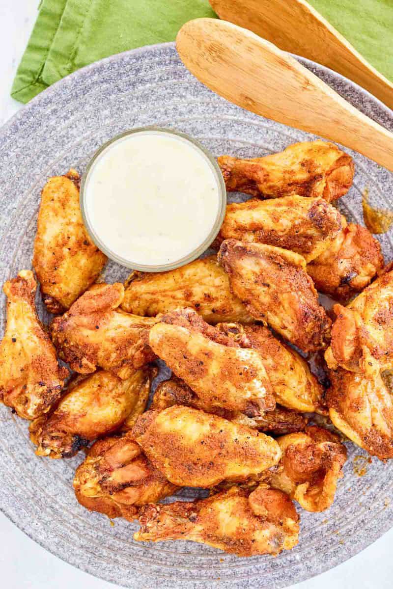 Copycat Wingstop Louisiana rub chicken wings and a small cup of ranch dressing.