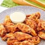 Copycat Wingstop Louisiana rub wings and a small cup of dipping sauce on a plate.