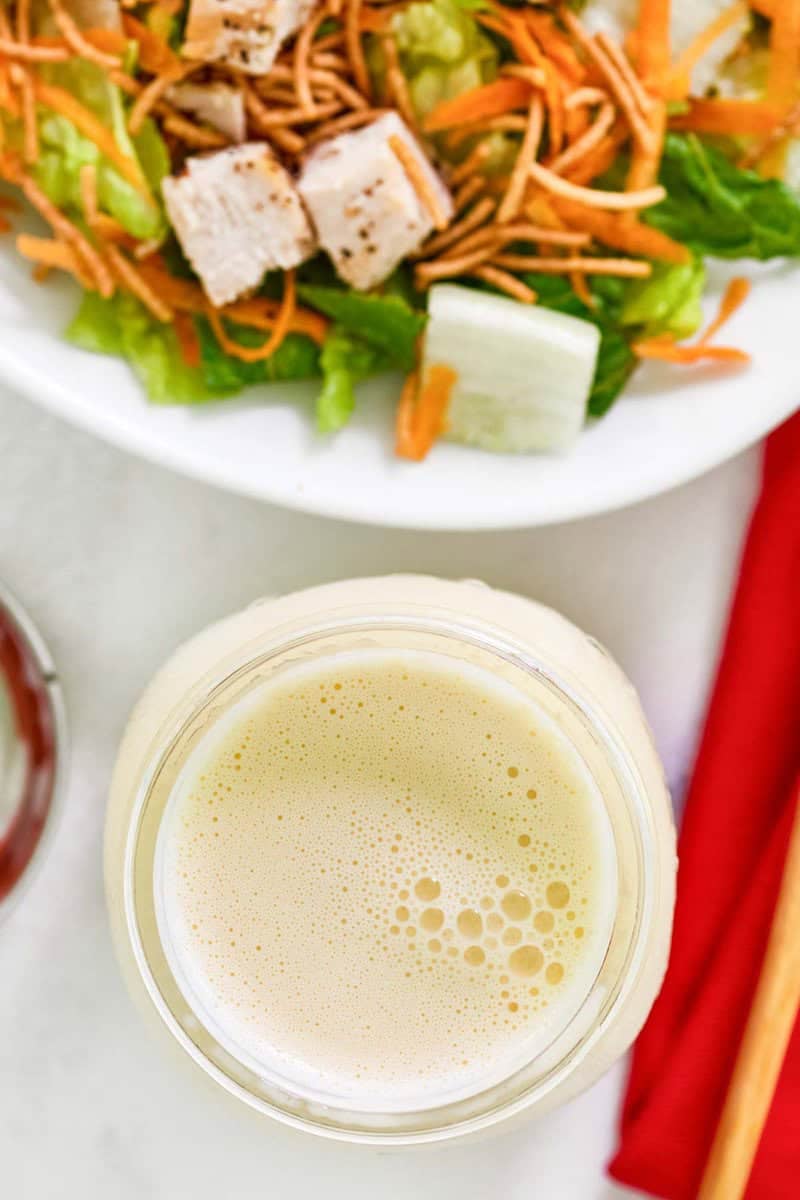 Copycat Applebee's oriental salad dressing in a jar next to a salad.